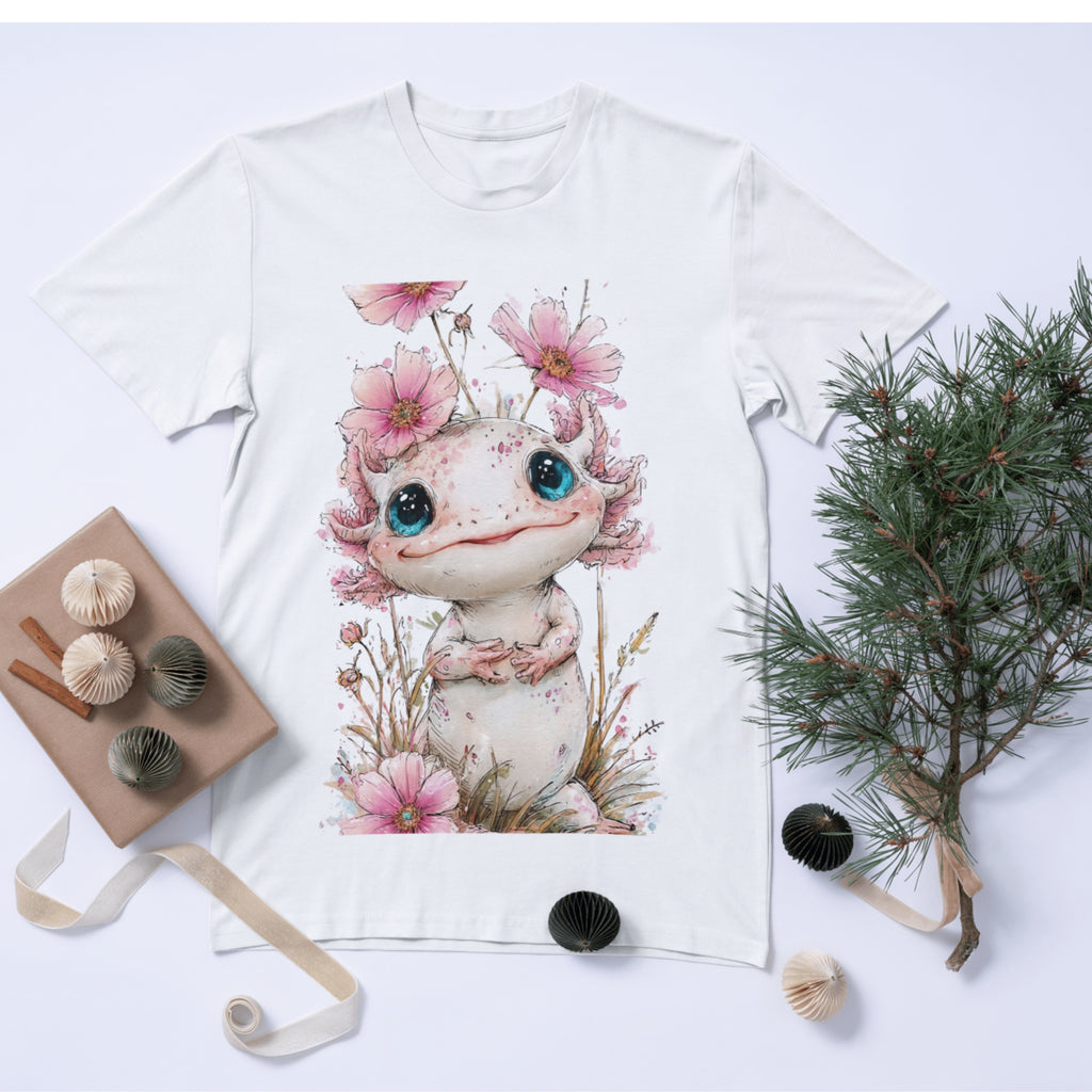White t-shirt with a cute creature design featuring flowers and plants, placed on a white surface with decorative items.